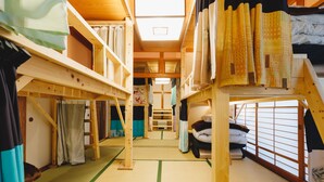 A traditional Japanese-style room with tatami flooring, wooden furniture, and sliding doors. - Couch Potato Hostel (Matsumoto)