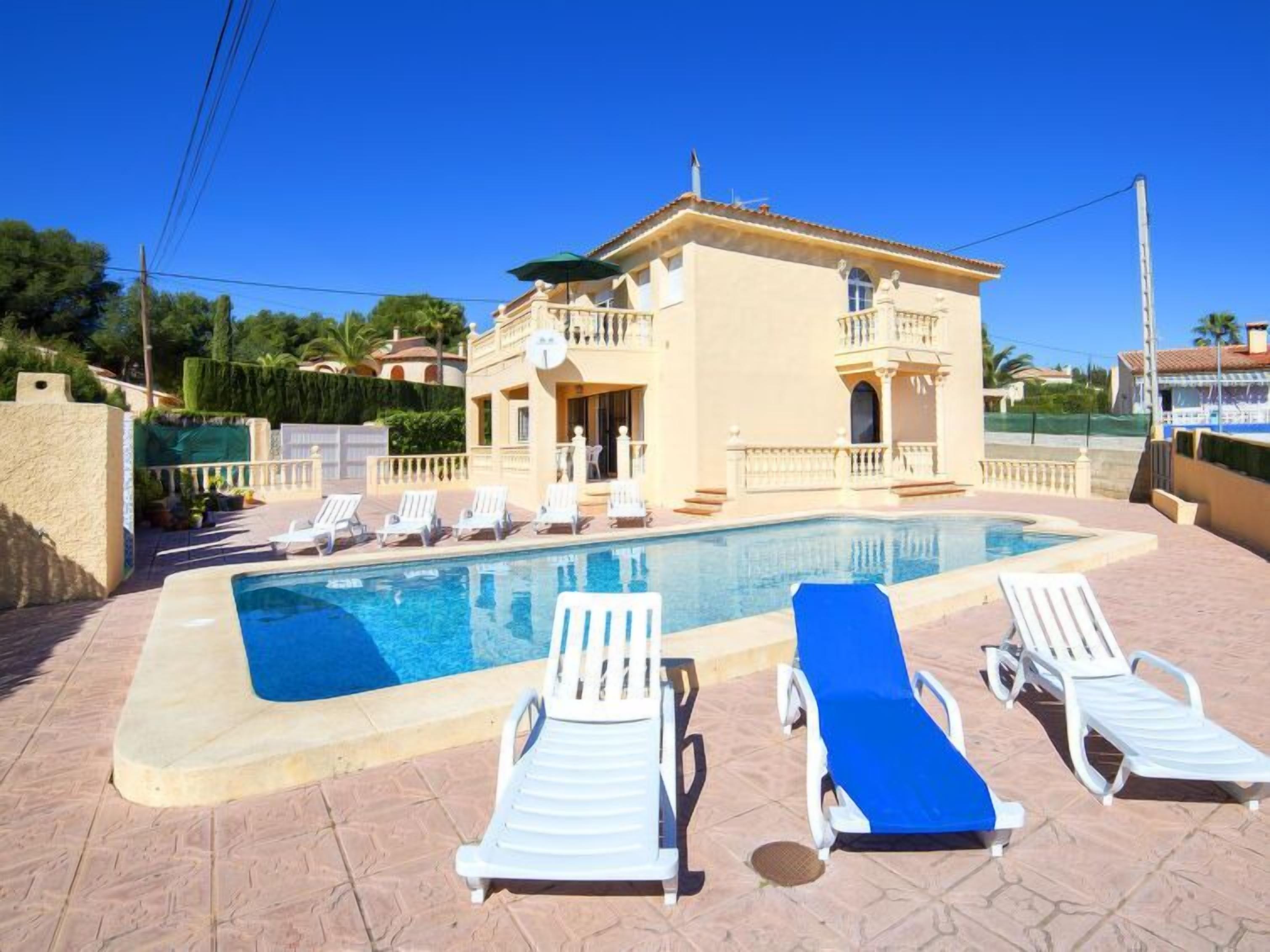 A pool area with lounge chairs and a building with balconies.