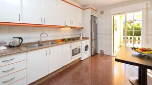 A modern kitchen with white cabinets, a granite countertop, a built-in oven, a washing machine, and a refrigerator. - Vacation home Gao by Interhome (Calpe/Calp)
