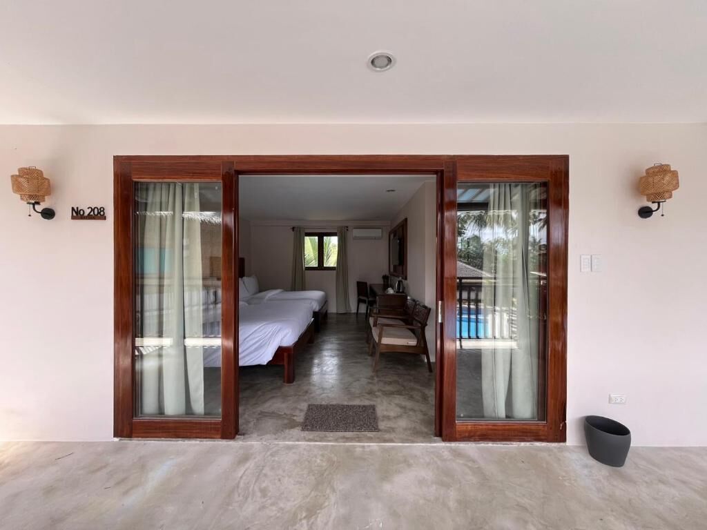 A room with a bed, a desk, and a view of a pool.
