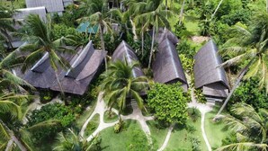A resort with thatched-roof villas surrounded by lush greenery and palm trees. - Ferra Resort Siargao (General Luna)