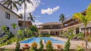 A resort with a swimming pool, palm trees, and a thatched-roof building. - Ferra Resort Siargao (General Luna)