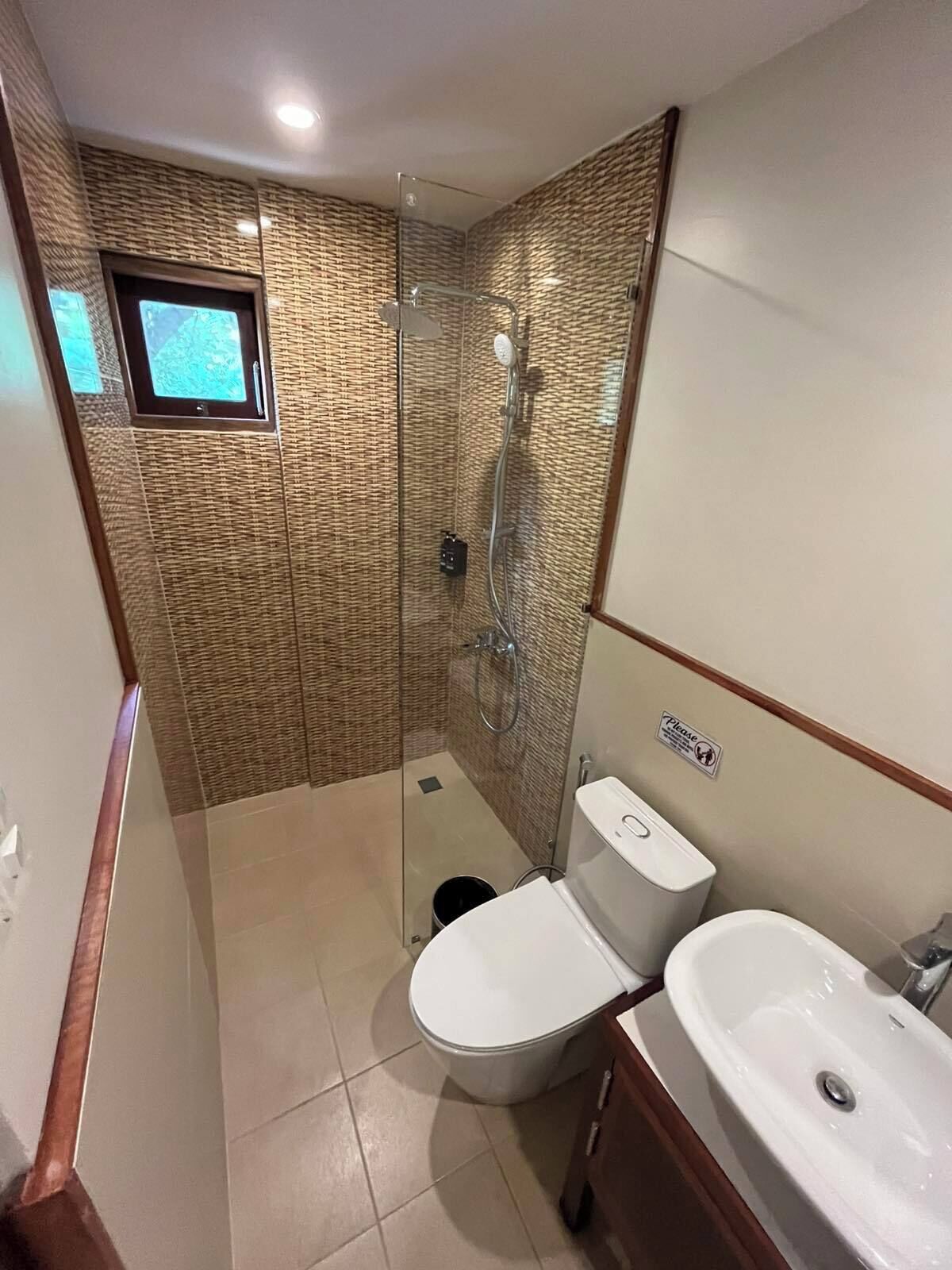 Casa de banho compacta com chuveiro em cabine de vidro, sanita e lavatório.
