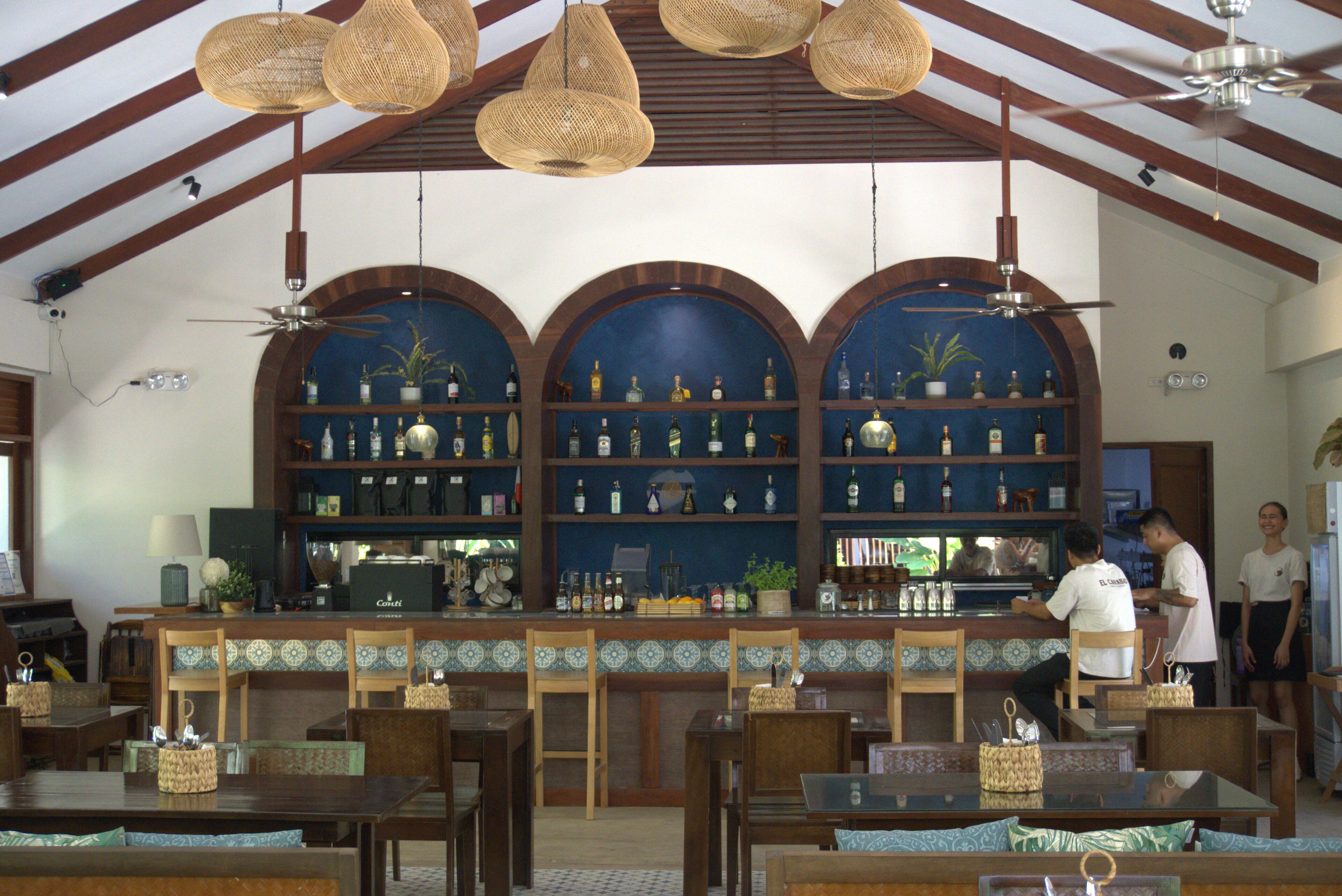A bar area with wooden furniture, a counter with bottles, and a ceiling fan.