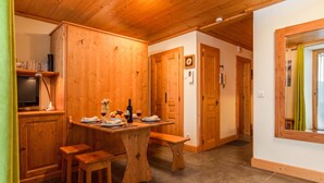 Un interno in legno con un tavolo da pranzo apparecchiato per due, una televisione e una panca.