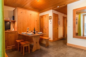 A wooden interior with a dining table set for two, a television, and a bench. - Apt Arsene1 Mont Blanc Views 3-min to Ski, Le Tour (Argentière), France (Le Tour (Argentière))