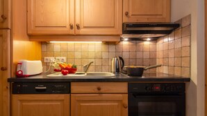 Una cucina con mobili in legno, una lavastoviglie Bosch, un forno Bosch e uno schienale in piastrelle.