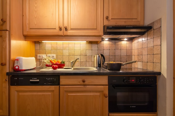 A kitchen with wooden cabinets, a Bosch dishwasher, a Bosch oven, and a tiled backsplash.