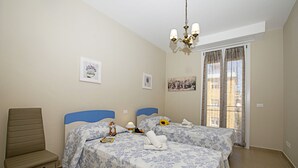 Une chambre avec deux lits, une chaise et un lustre.