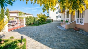 A paved driveway leading to a gated entrance with a white car parked inside.