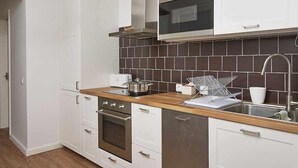 Une cuisine moderne avec des armoires blanches, une hotte de cuisinière en acier inoxydable, un four à micro-ondes et un plan de travail en bois.