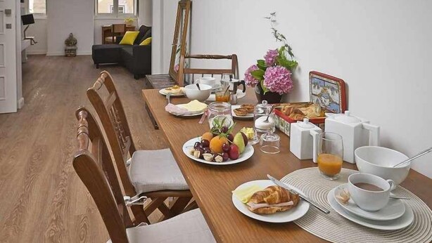 Une table de petit-déjeuner dressée avec des assiettes remplies de nourriture, une tasse de café et un vase de fleurs.