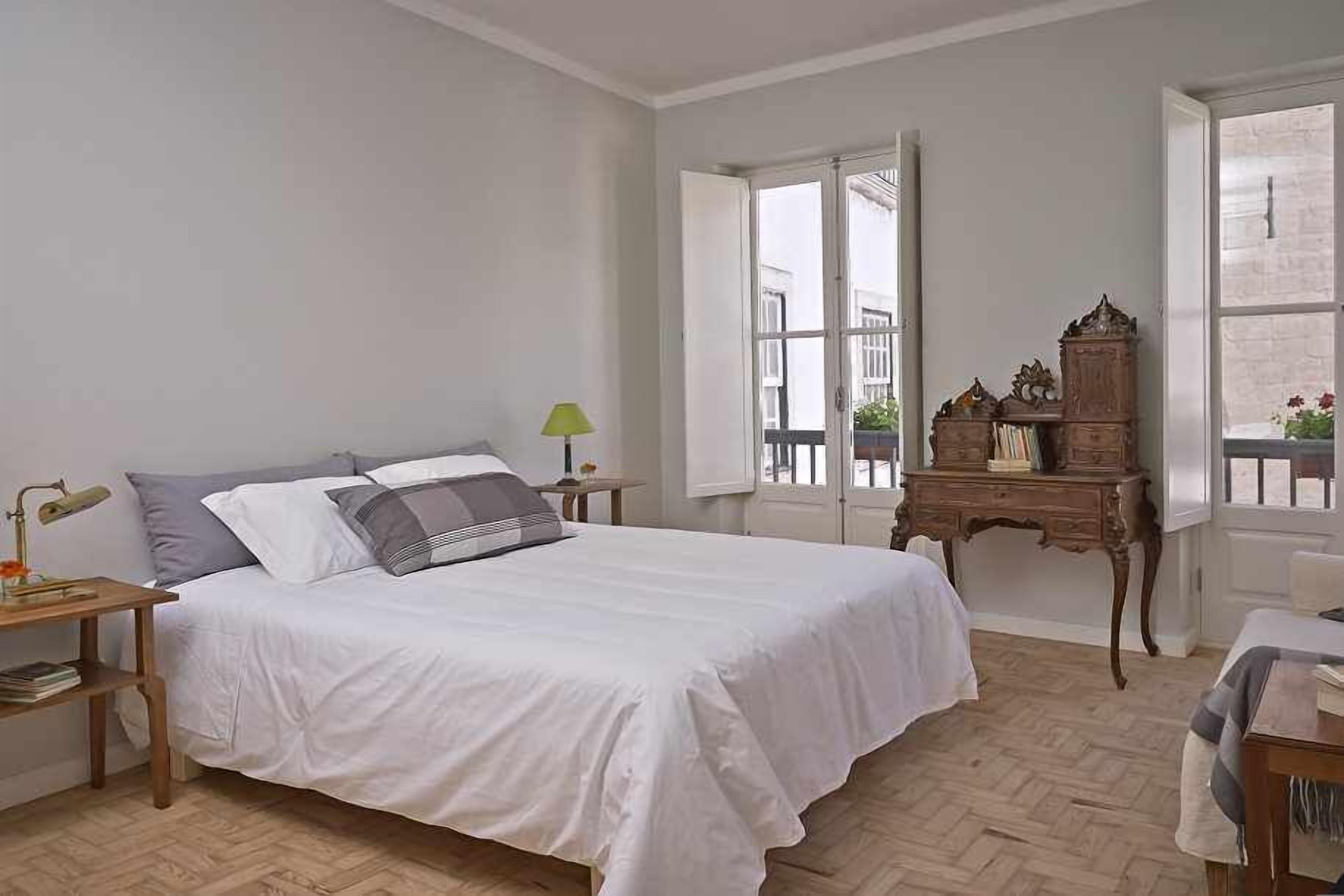 Ein Schlafzimmer mit einem Bett, Nachttischen, einer Kommode und einem Fenster.