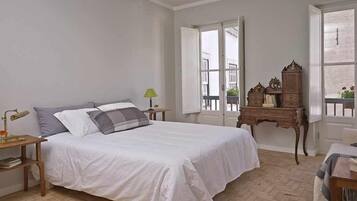 Ein Schlafzimmer mit einem Bett, Nachttischen, einer Kommode und einem Fenster.
