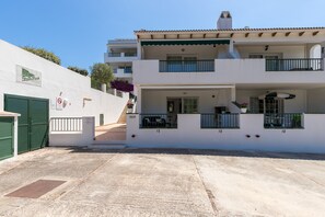 A two-story building with a balcony, a covered porch, and a gated entrance. - Newly Renovated Apartment "Enzo" with Wi-Fi, Terrace & Pool (Son Parc)