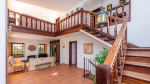 Un vaste espace de vie agrémenté d’un escalier en bois, d’une cheminée et d’un coin salon avec un canapé et des fauteuils.