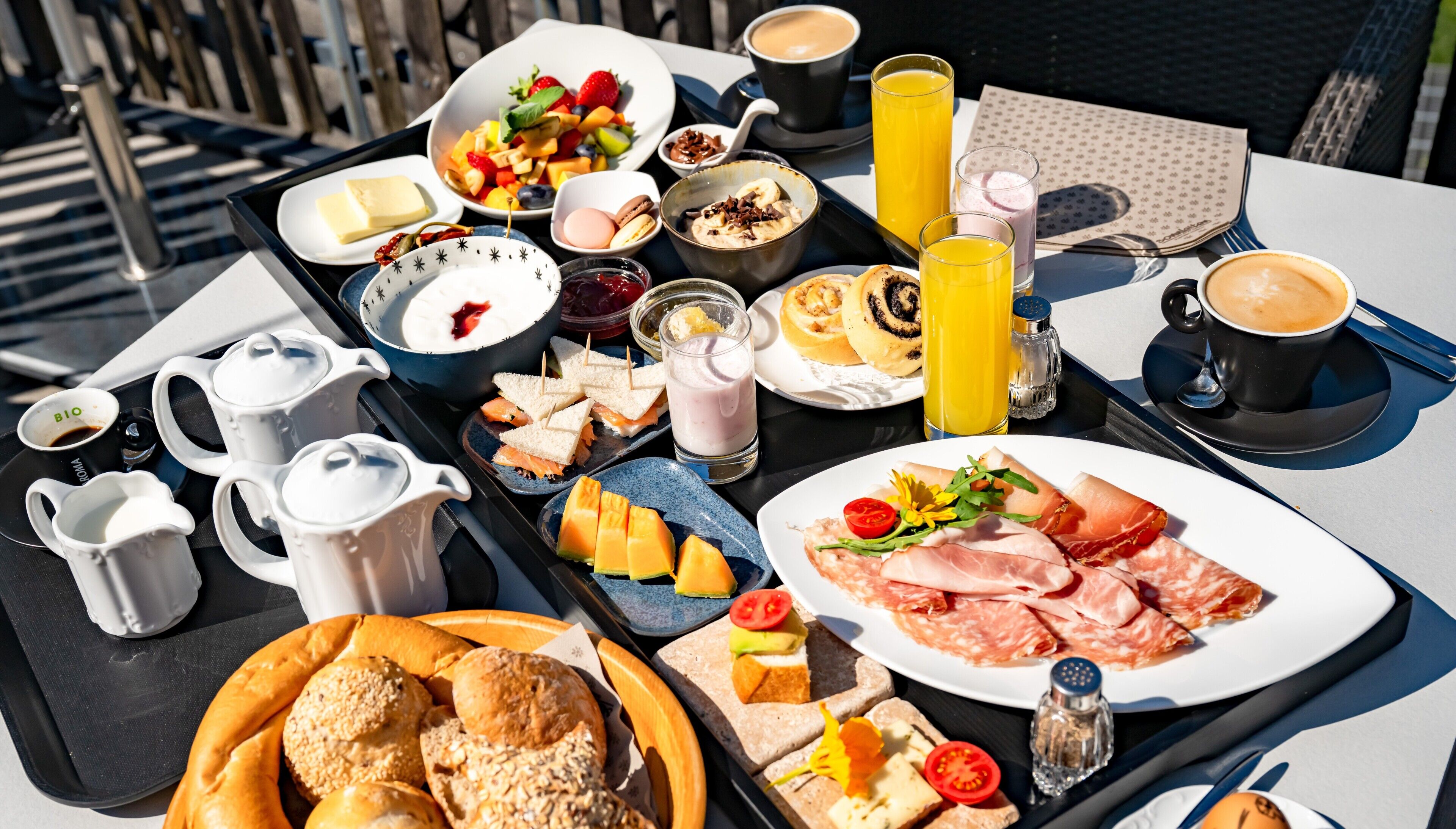 Ein Frühstückswagen mit verschiedenen Speisen und Getränken, darunter Brot, Käse, Schinken und Kaffee.