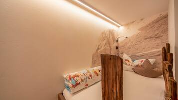 A bedroom with a wooden headboard, a bed with patterned bedding, and a wall-mounted light fixture.