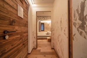 A hallway with wooden walls, a bed with a view, and a geometric light fixture.