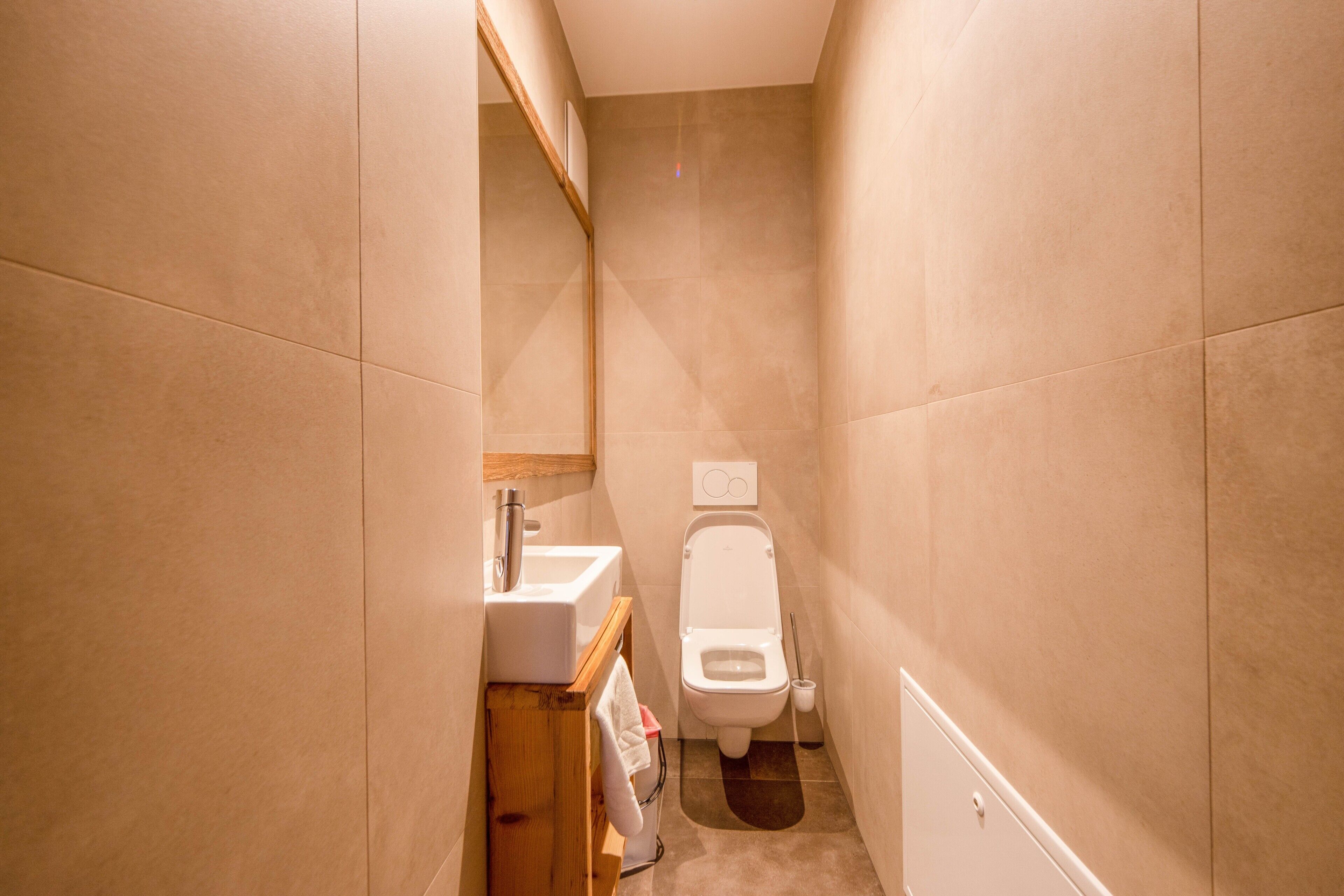 Une petite salle de bain étroite, équipée de toilettes, d’un lavabo et d’un miroir.