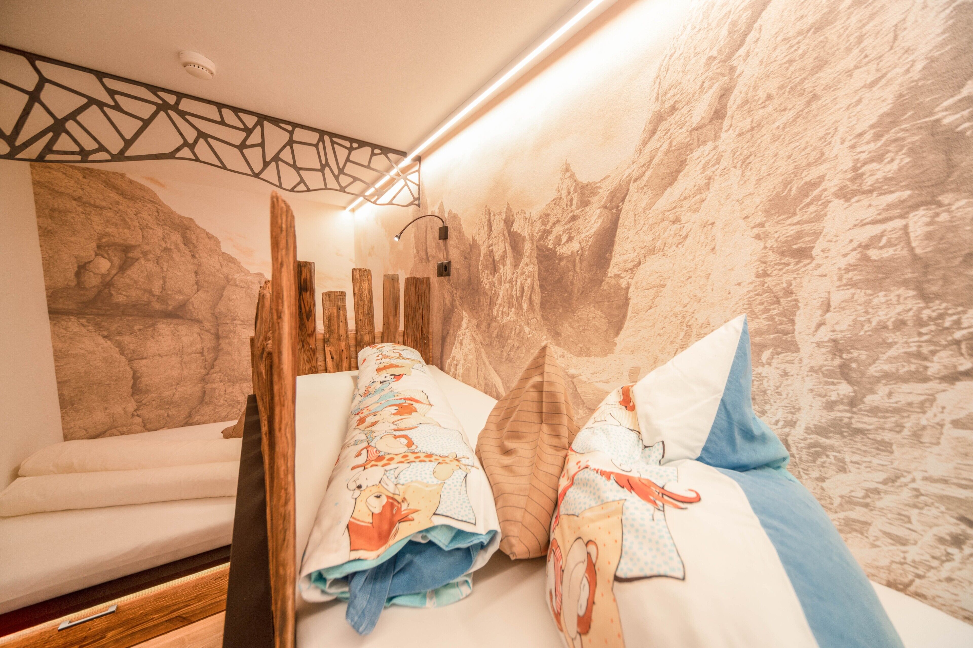 Ein Zimmer mit einem Bett, einem Holzkopfende, einem Wandbild und einer Deckenleuchte.