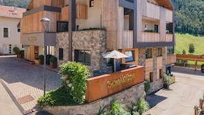 Un bâtiment moderne avec une façade en pierre, des éléments décoratifs en bois et une enseigne indiquant « Somleiten ».