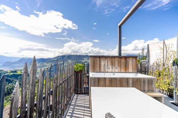 A modern outdoor bathroom with a wooden deck, a sink, and a view of mountains.