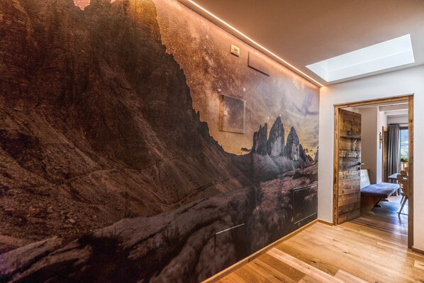 A room with a large wall mural, wooden flooring, and a skylight.
