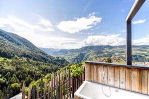 A balcony with a wooden railing overlooking a mountainous landscape.