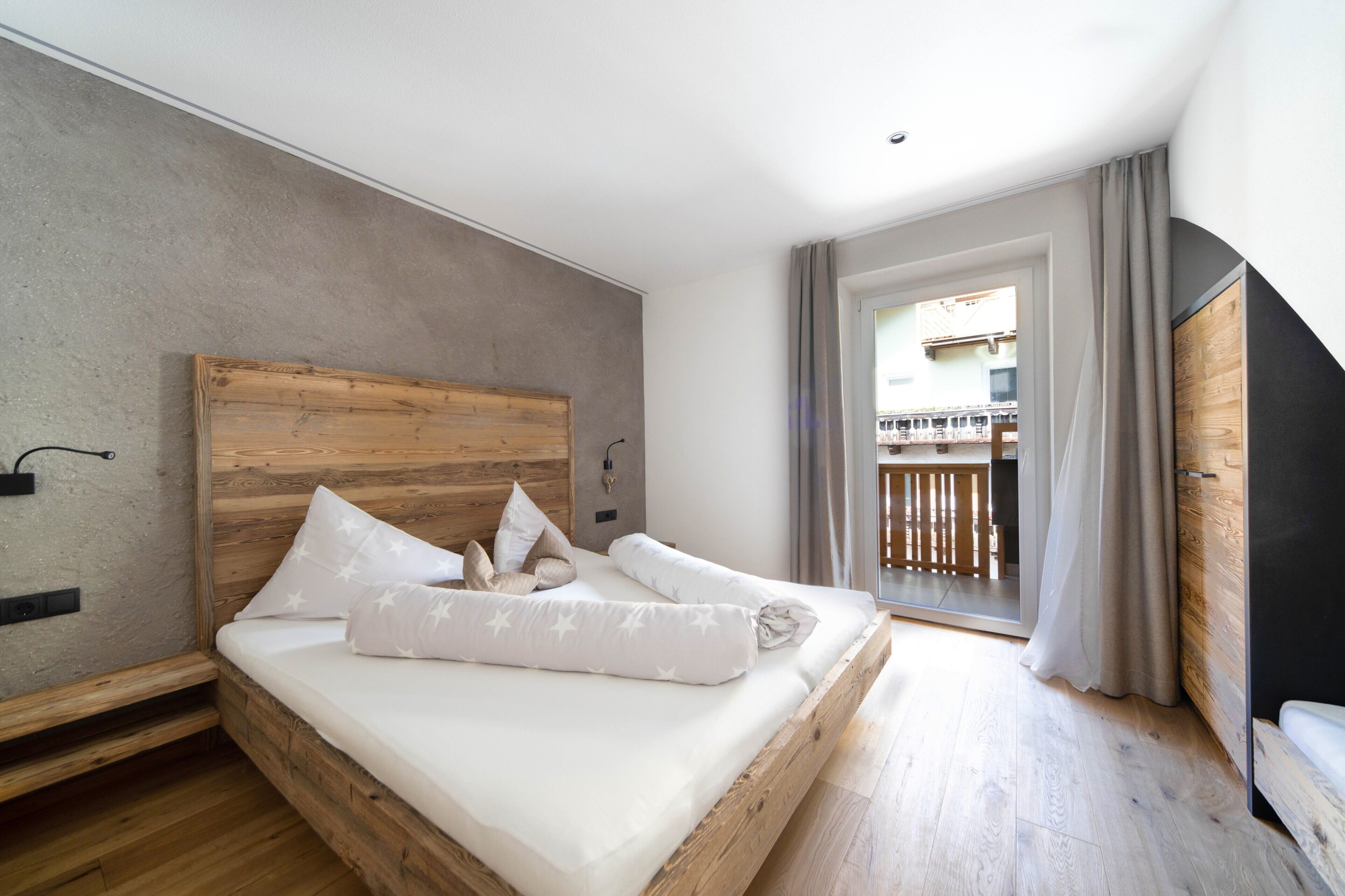 Un dormitorio con cabecera de madera, cama con ropa blanca y vistas a un balcón, con un diseño moderno.