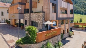 Un edificio moderno con facciata in pietra, dettagli in legno e un cartello con scritto 'Somleiten'.