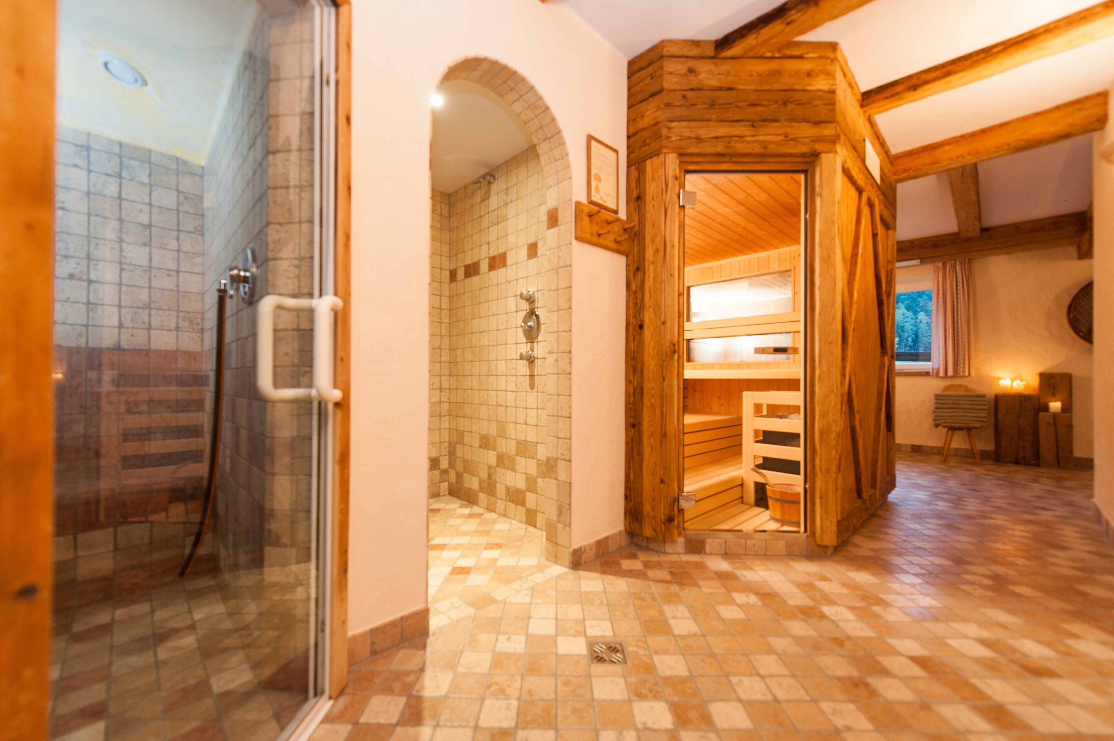 Een badkamer met douche, betegelde wanden en houten balken.