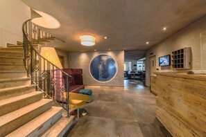 Un intérieur moderne agrémenté d’un escalier en colimaçon, d’une décoration murale circulaire et d’un comptoir d’accueil en bois.