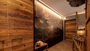 Un intérieur en bois avec un sol en pierre, un banc et une fresque murale représentant un paysage de montagne.