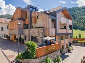 Un bâtiment moderne avec une façade en pierre, des éléments décoratifs en bois et une enseigne indiquant « Somleiten ».