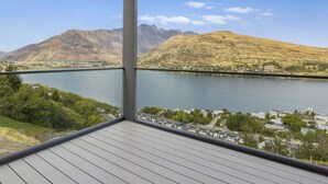 Ein Balkon mit Blick auf einen See, Berge und eine Stadt.