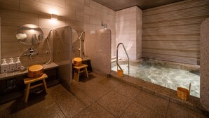 Ein modernes Badezimmer mit einer Badewanne, zwei hölzernen Hockern, einem Spiegel und einer Duschkabine.