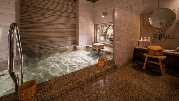 Ein modernes Badezimmer mit Spa-Ausstattung, einer Whirlwanne, Holzschemeln, einer Holzbank und einem großen Spiegel.