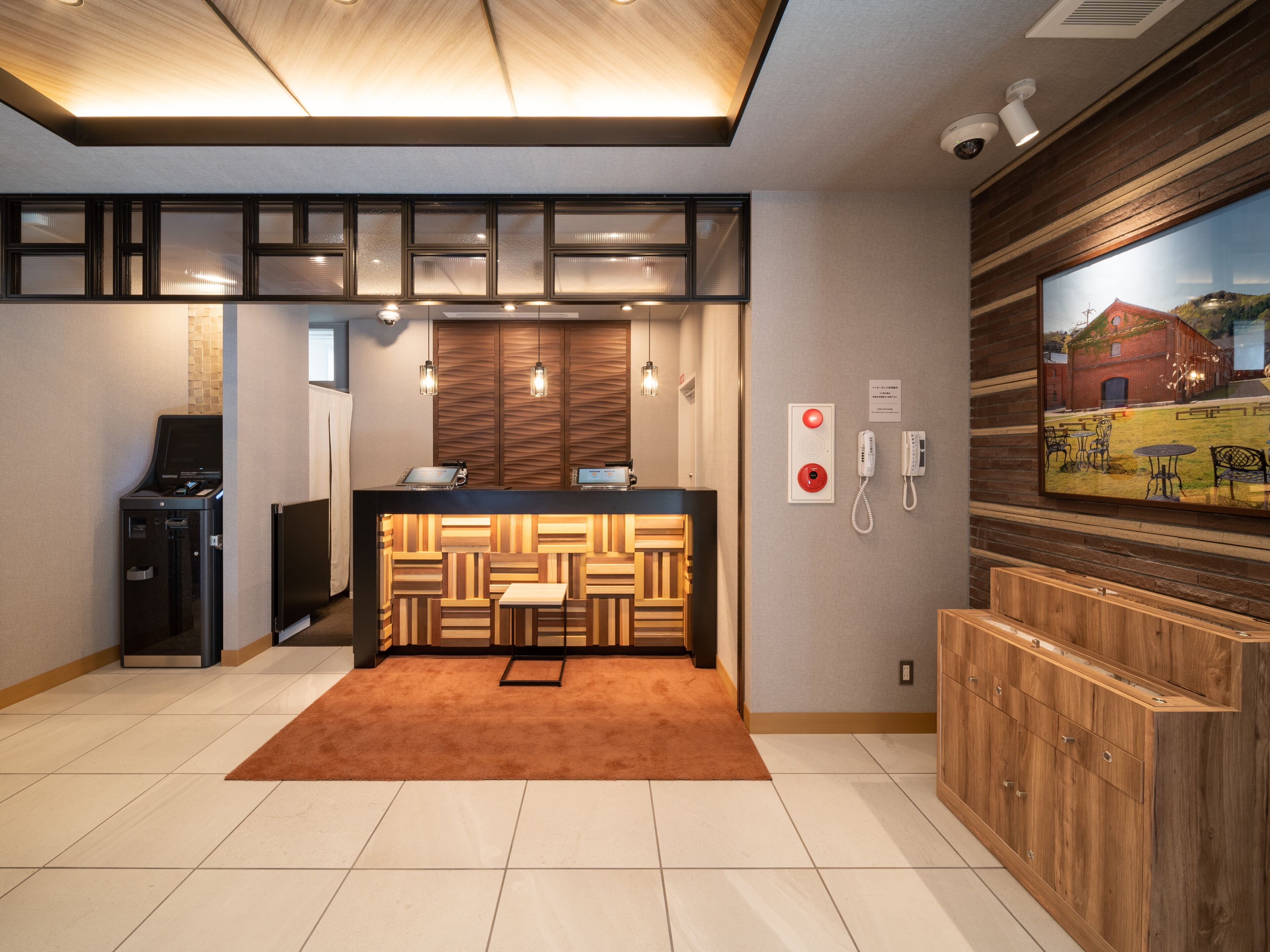 A modern hotel lobby with a reception desk, a wooden accent wall, a large window with a view, and a security camera.