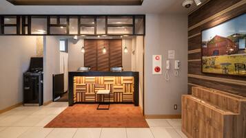 A modern hotel lobby with a reception desk, a wooden accent wall, a large window with a view, and a security camera.