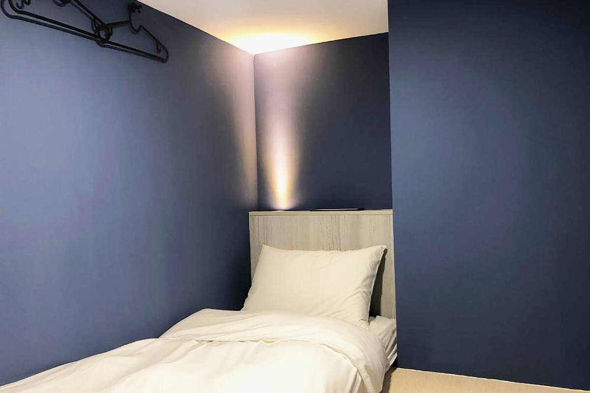 A single bed with a white headboard in a room with dark blue walls.