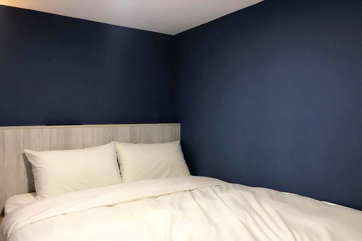 A bed with white bedding in a room with dark blue walls.
