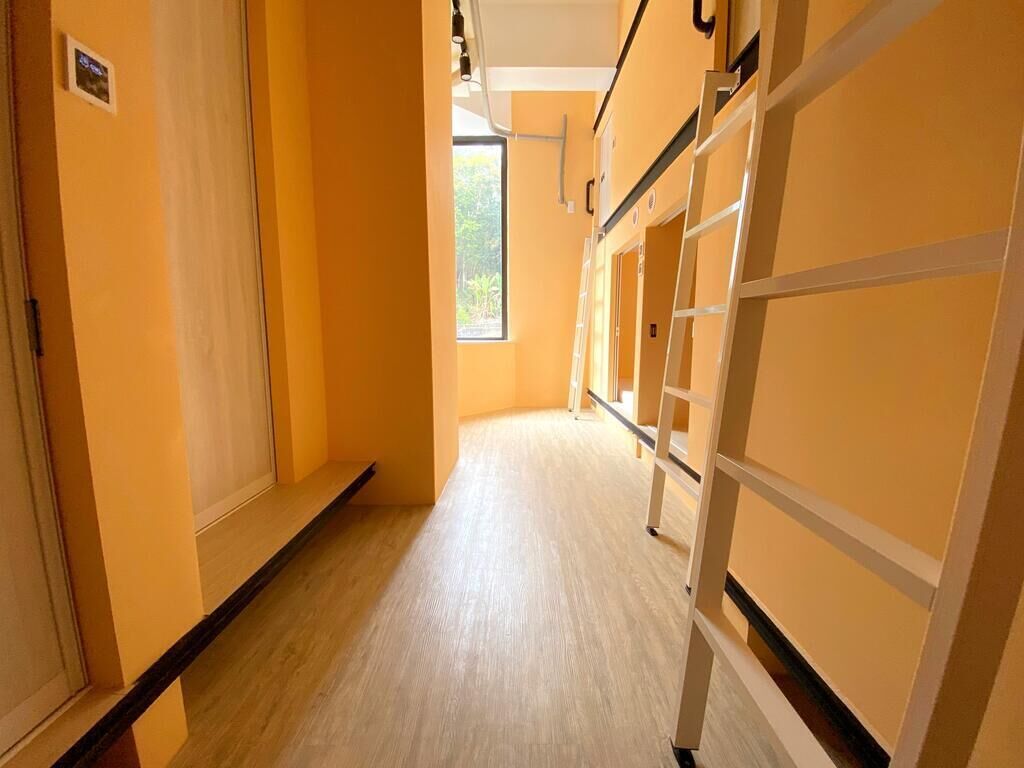 A corridor with bunk beds and a window at the end.