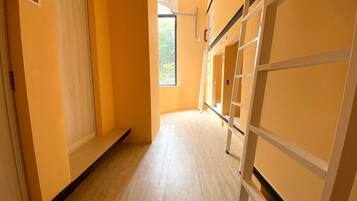 A corridor with bunk beds and a window at the end.