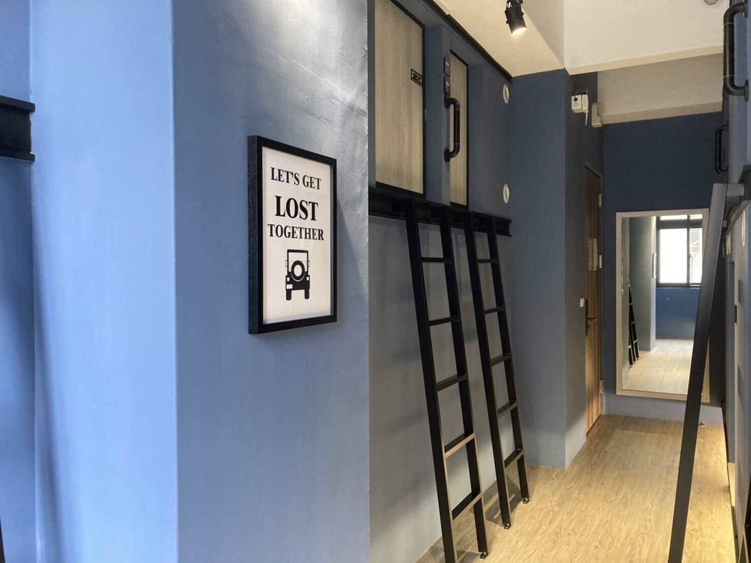 A hallway with a sign that reads "LET'S GET LOST TOGETHER" and a black ladder leaning against the wall.