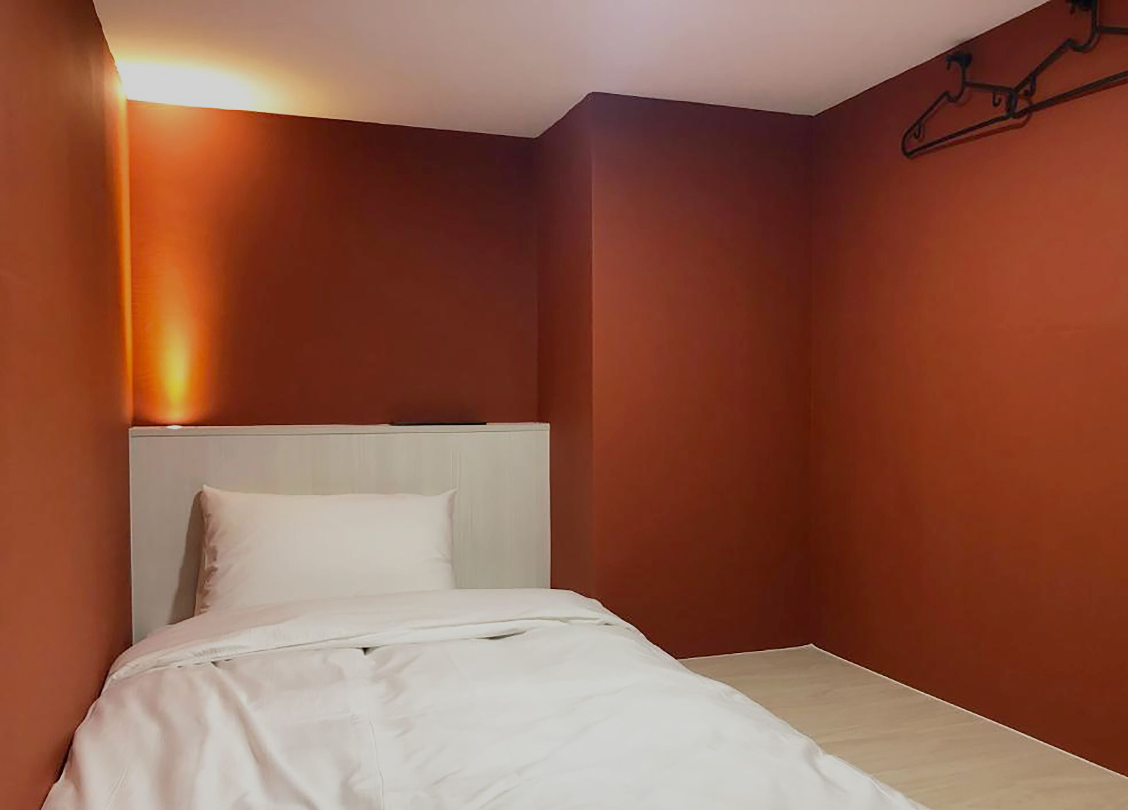 A bedroom with a bed, a headboard, and a wall-mounted coat rack.