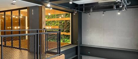 Un interior moderno con un entresuelo, barandales metálicos y una pared verde con plantas.