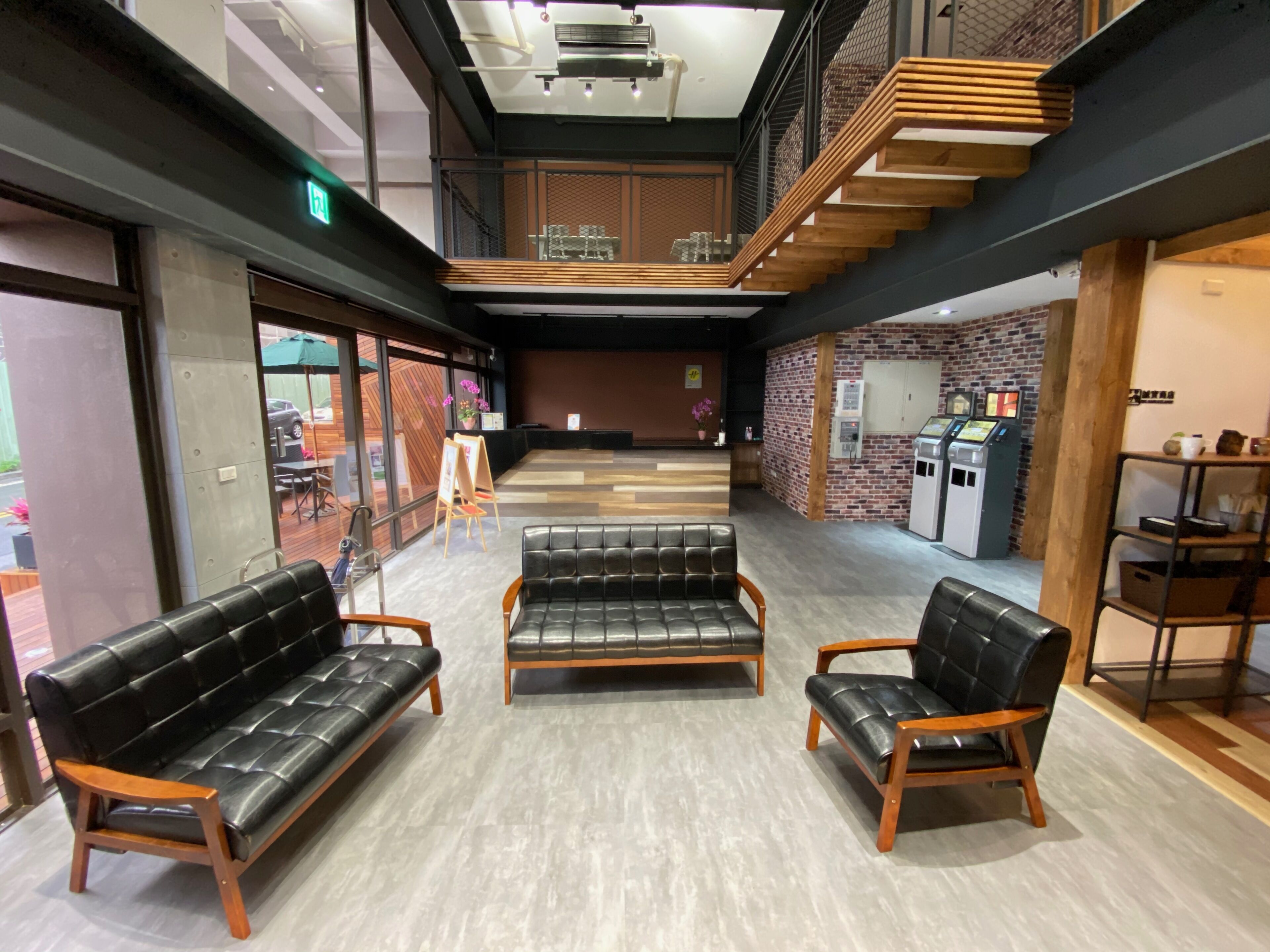 A spacious lobby with a high ceiling, a staircase, and a reception area.