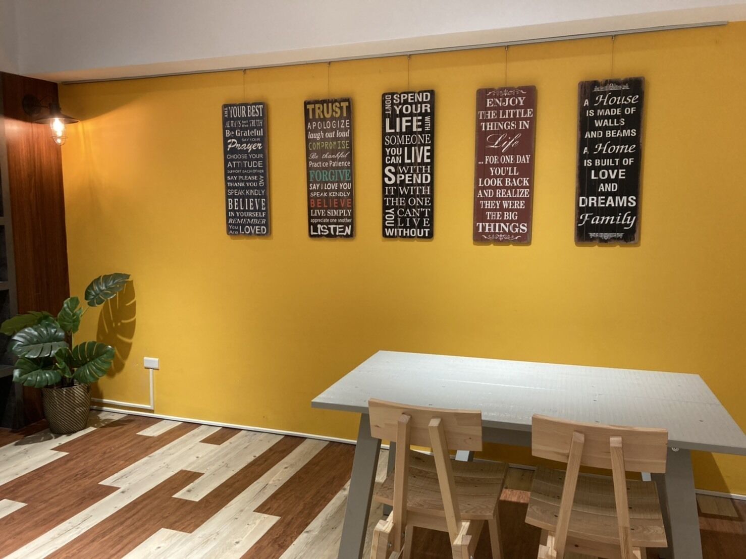 A dining area with a yellow wall and a wooden table.