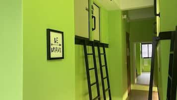 A hallway with green walls, a framed motivational quote, and a black ladder leaning against the wall.